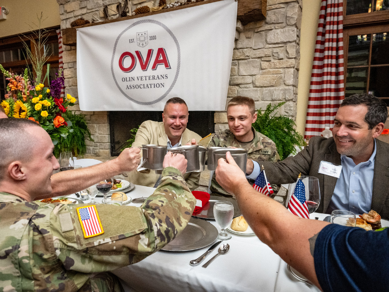 OVA members sharing a toast beneath the Olin Veterans Association banner